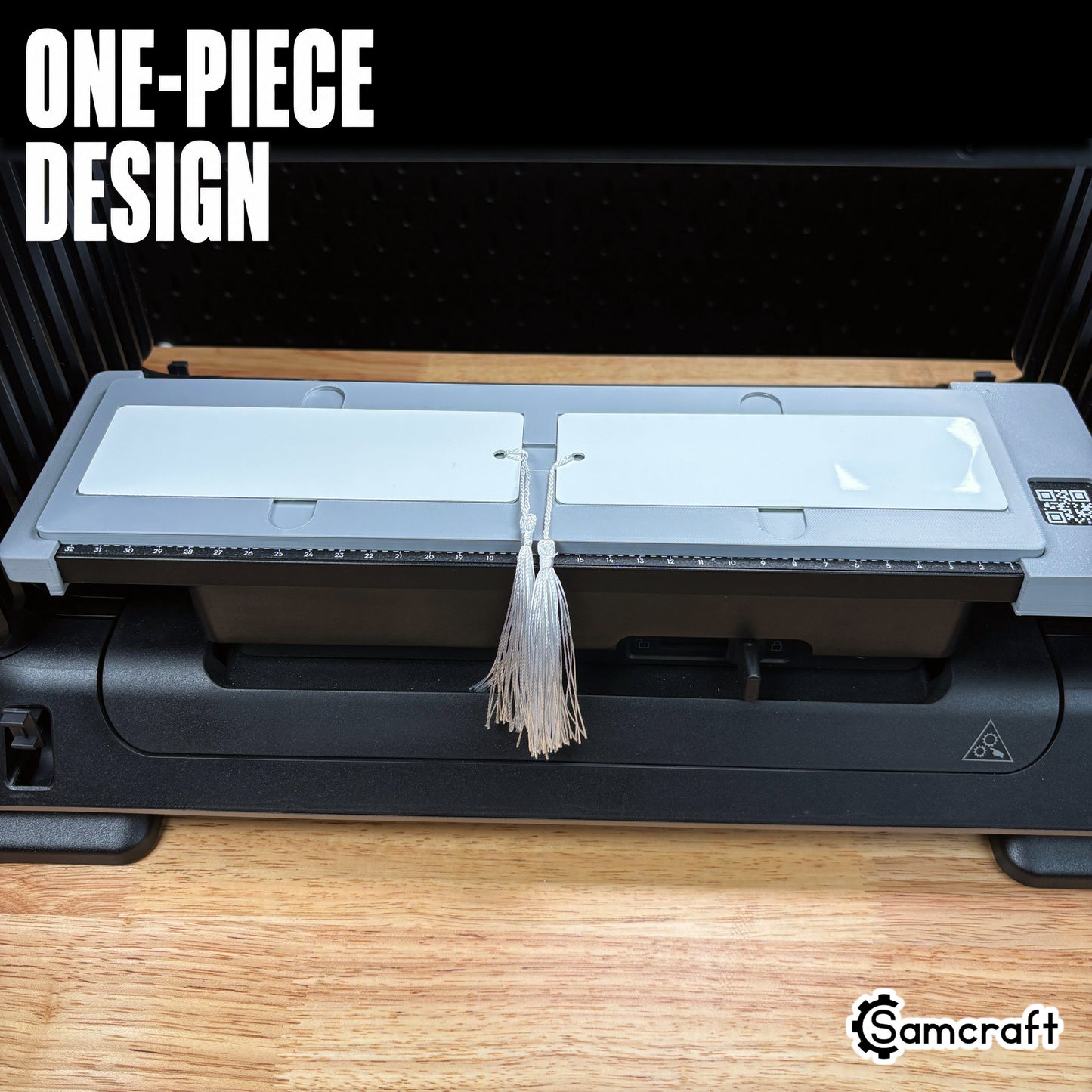 Front view of the one-piece Samcraft 2x6 Bookmark Jig holding two white metal bookmarks with hanging tassels on the eufyMake E1 UV printer.
