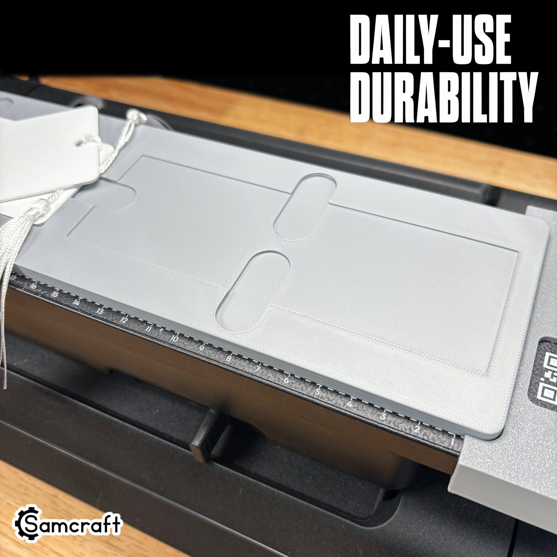 Detail of the Samcraft 2x6 Bookmark Jig's recessed pocket and finger-relief cutouts in a durable gray tray, mounted on the eufyMake E1 UV printer bed.