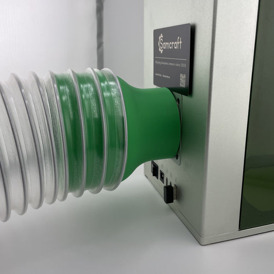 Samcraft green 4 inch exhaust hose adapter fitted to the rear of an xTool F1 with flexible ducting clamped on.