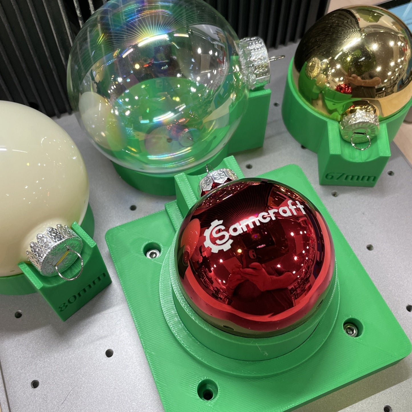 Samcraft green ball ornament jig in an xTool F1 Ultra, holding a red glass ornament engraved with the Samcraft logo.