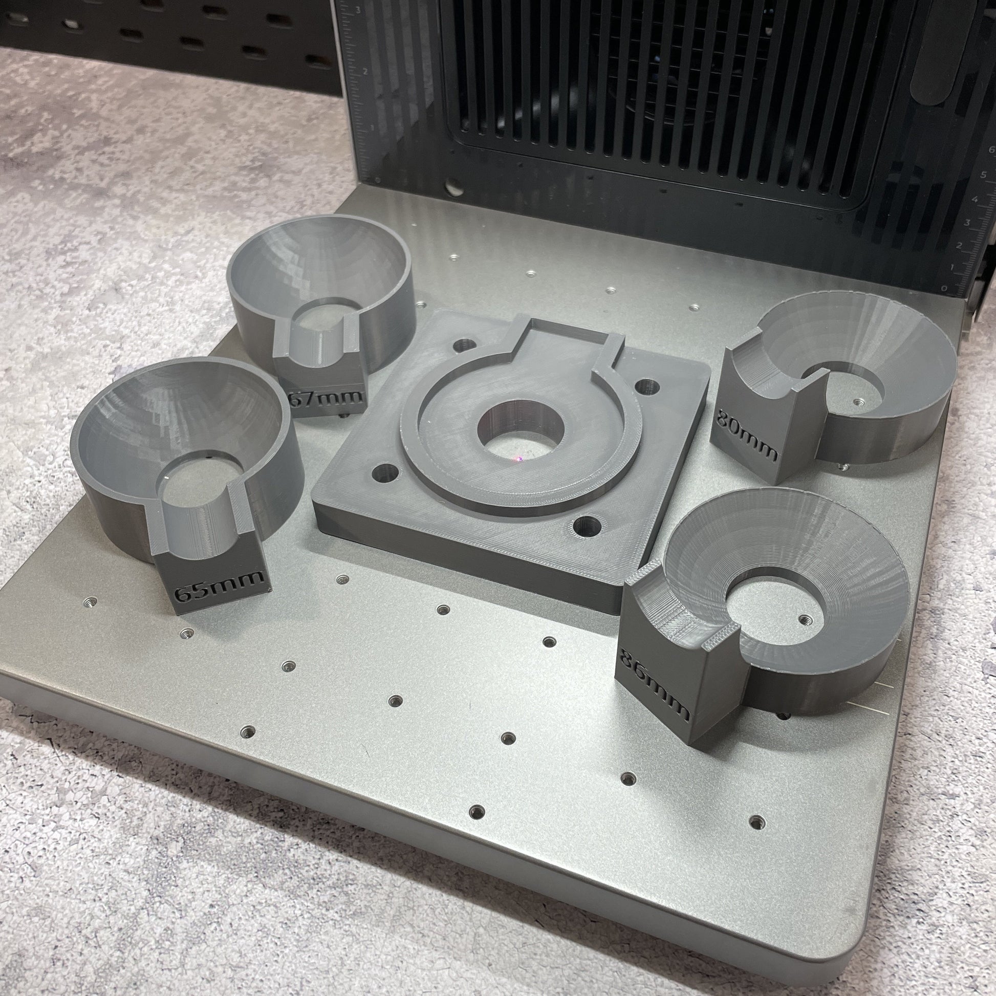 Samcraft ball ornament jig on the xTool F2 Ultra bed, showing the central round recess and the size-stepped holders.