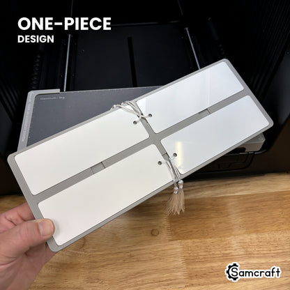 Hand holding the one-piece Samcraft 2x6 bookmark jig for the xTool Omni, four pockets in a single molded tray.