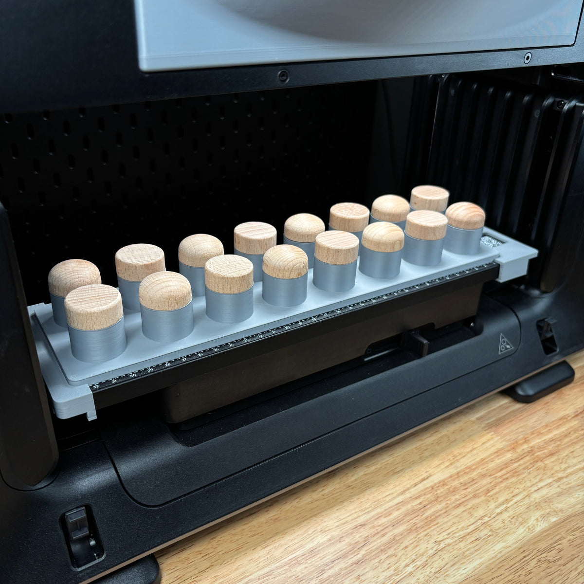 Samcraft bottle stopper jig on the eufyMake E1 print bed, holding a row of wood-topped bottle stoppers upright.