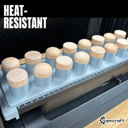 Heat-resistant Samcraft Bottle Stopper Jig holding wood-topped bottle stoppers in gray recesses with built-in alignment ruler on the eufyMake E1.