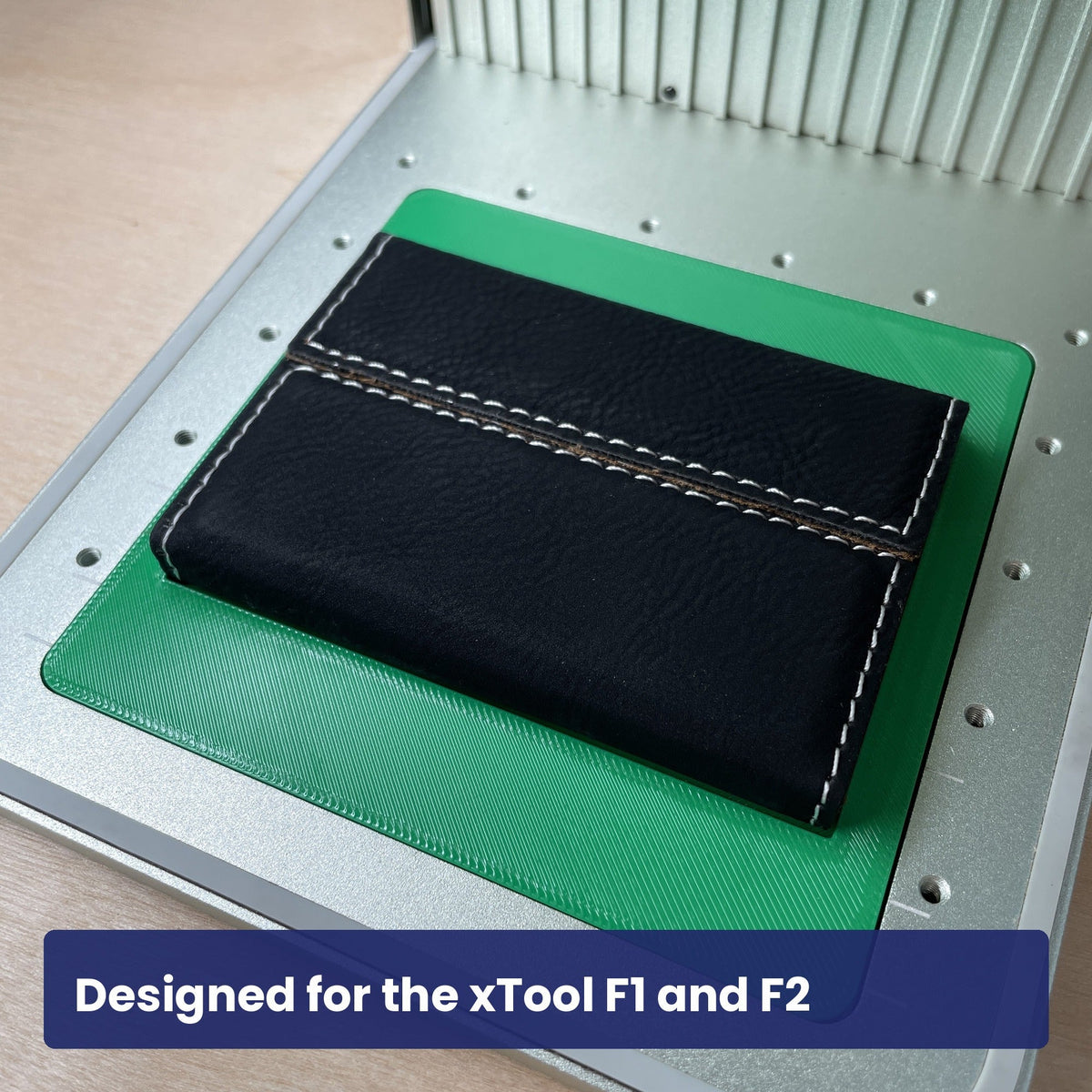 Samcraft business card case jig in the xTool F1 base plate with a closed black leatherette card case seated on it.