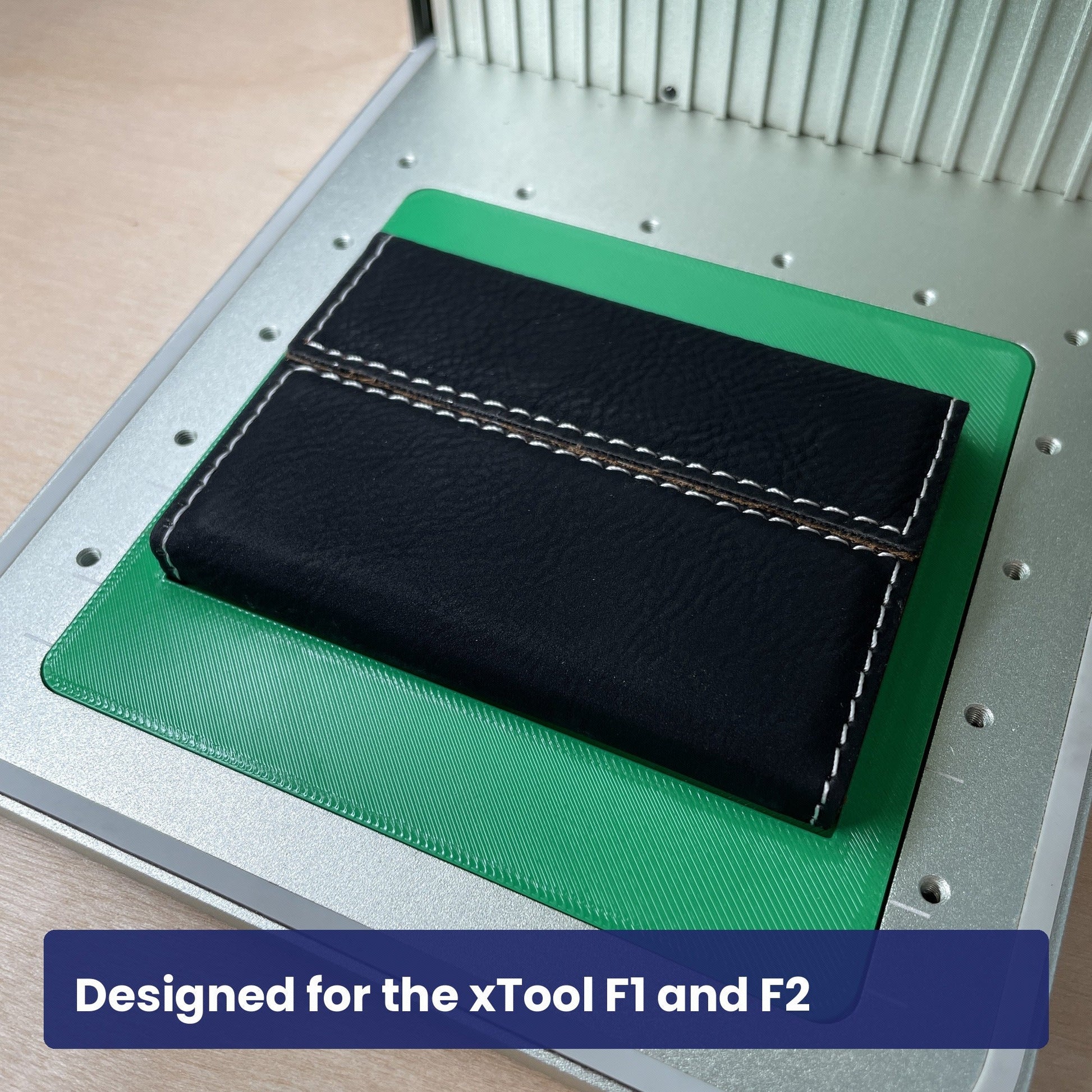 Samcraft business card case jig in the xTool F1 base plate with a closed black leatherette card case seated on it.