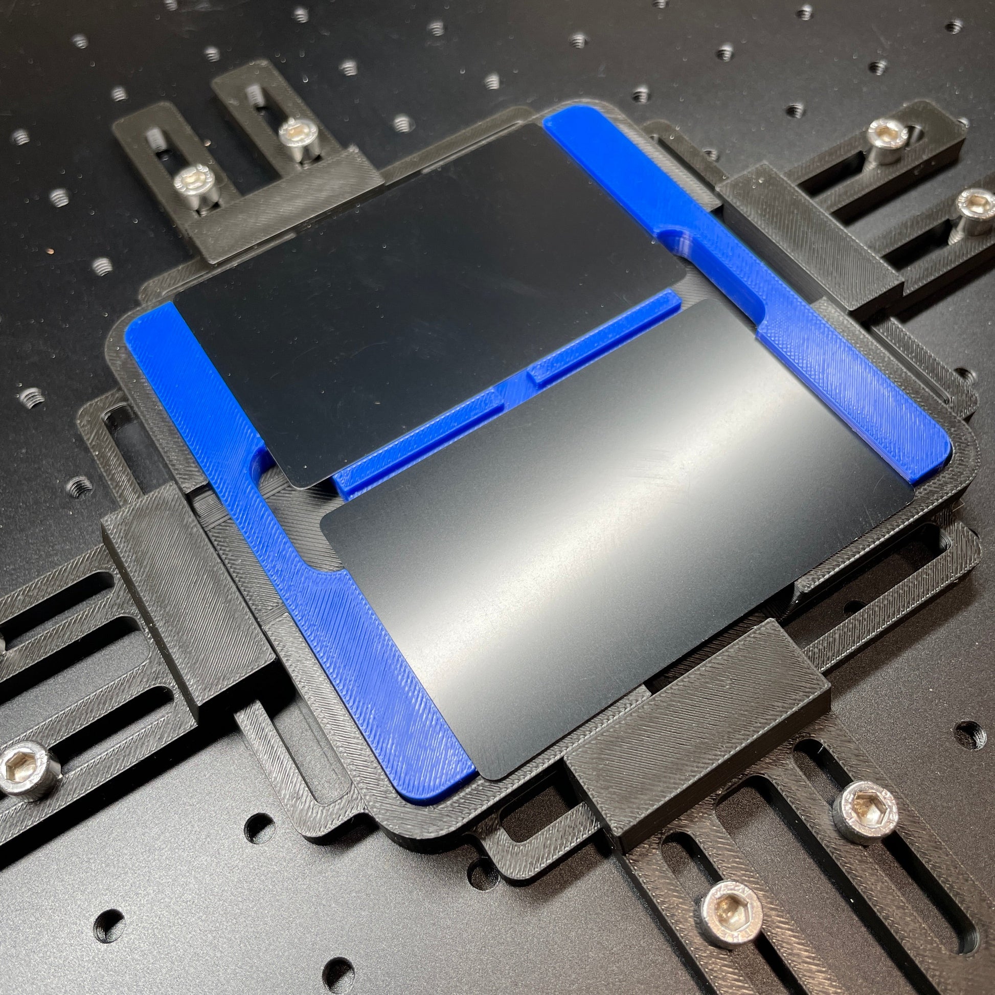 Samcraft blue business card jig on a ComMarker laser bed, holding a black metal business card.