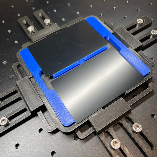 Samcraft blue business card jig on a ComMarker laser bed, holding a black metal business card.