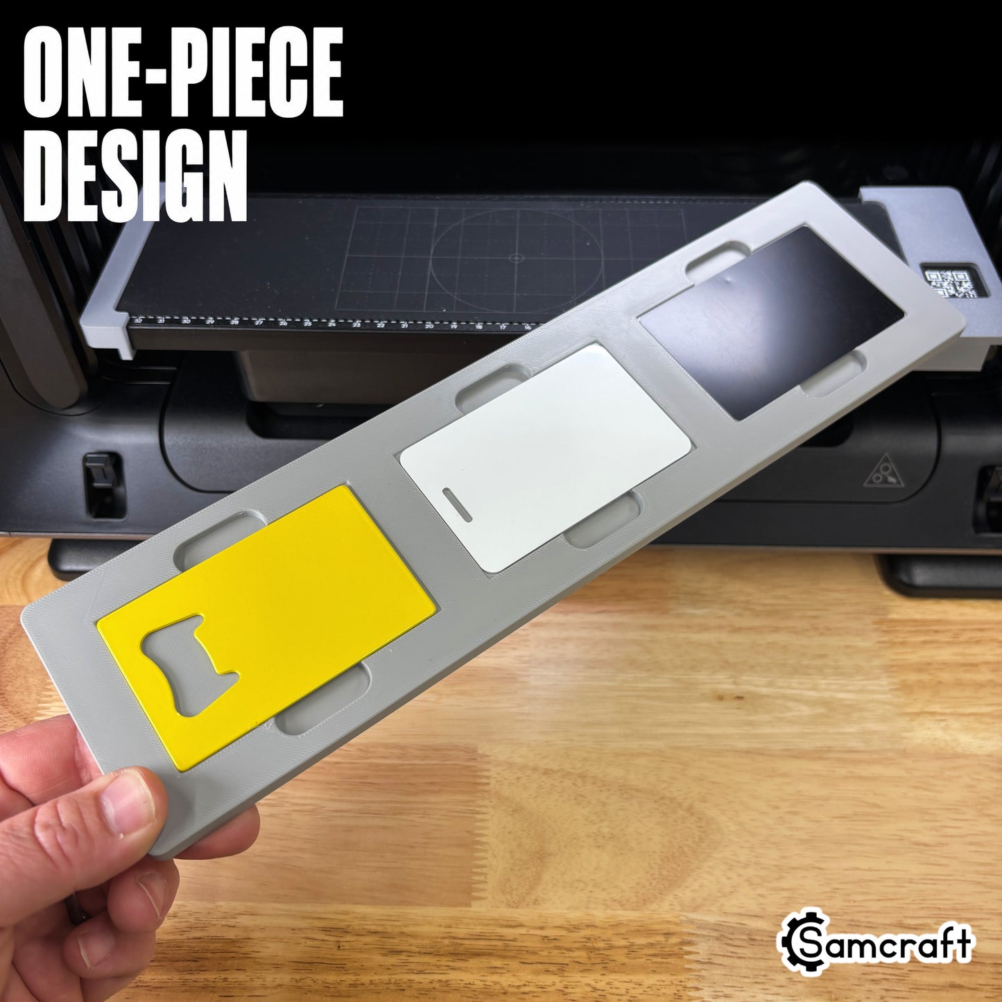 One-piece Samcraft Business Card Jig held in hand above the eufyMake E1 print bed, loaded with three cards