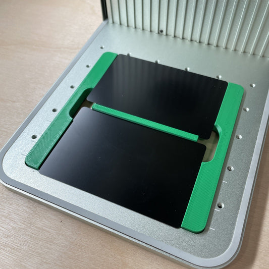 Samcraft business card jig in an xTool F1 laser bed, holding two black metal business cards.