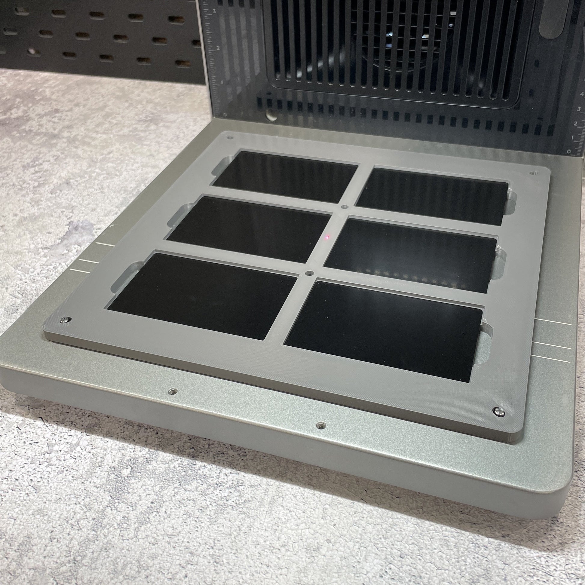 Samcraft business card jig on the xTool F2 Ultra bed, holding six black metal business cards.