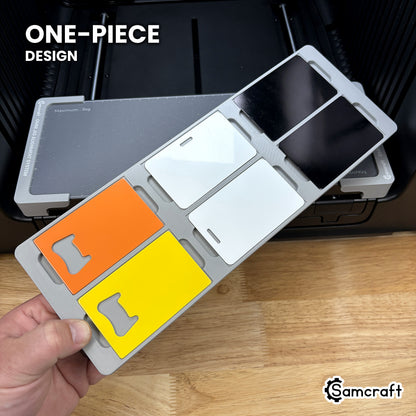 Hand holding the one-piece Samcraft business card jig for the xTool Omni, six card blanks seated in a single molded gray tray.
