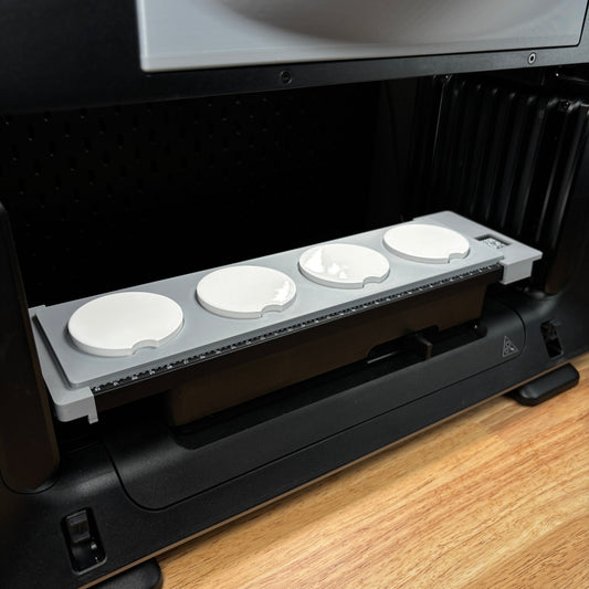 Samcraft car coaster jig on the eufyMake E1 print bed, holding four round white car coasters in circular recesses.