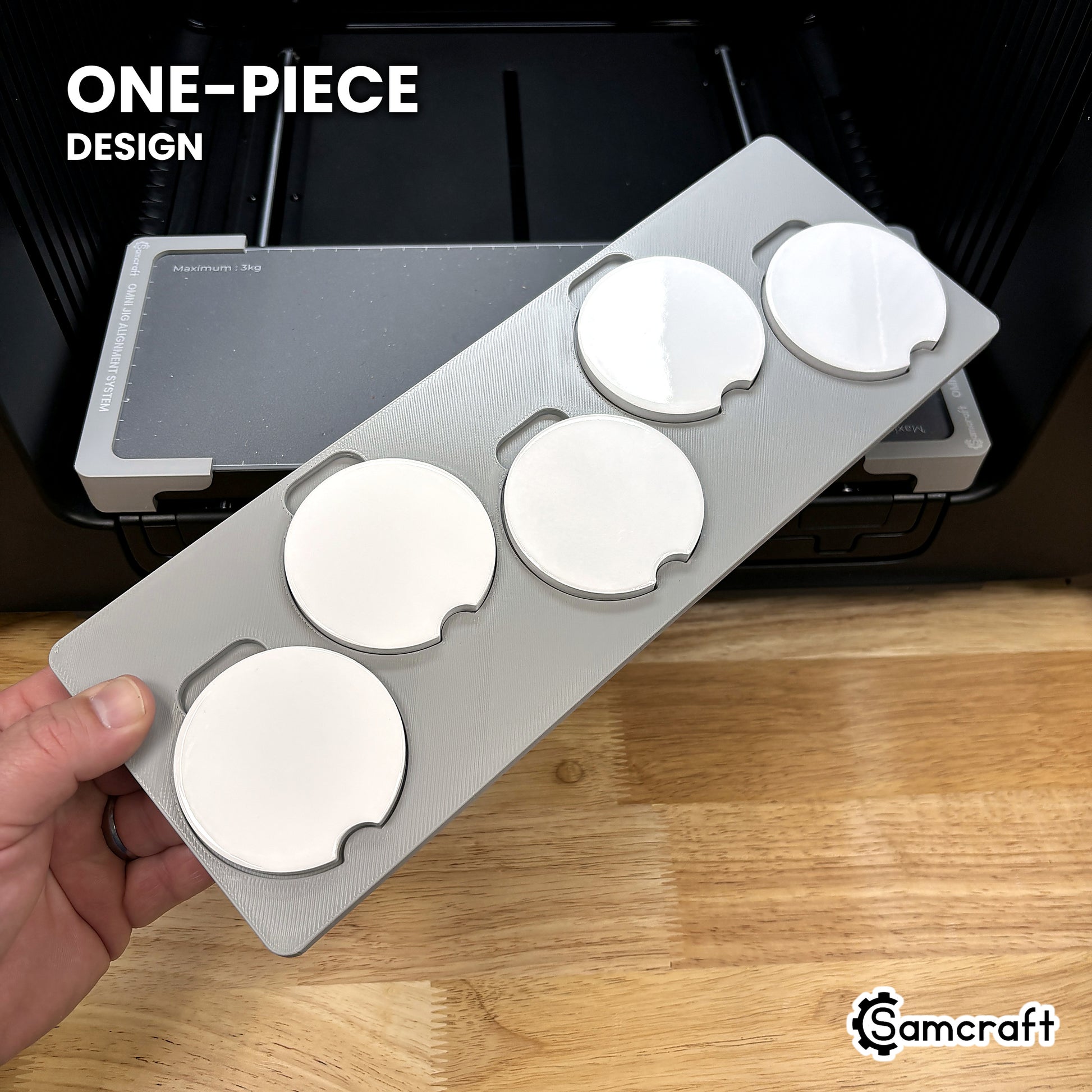 Hand holding the one-piece Samcraft car coaster jig for the xTool Omni, five coasters seated in a single molded tray.
