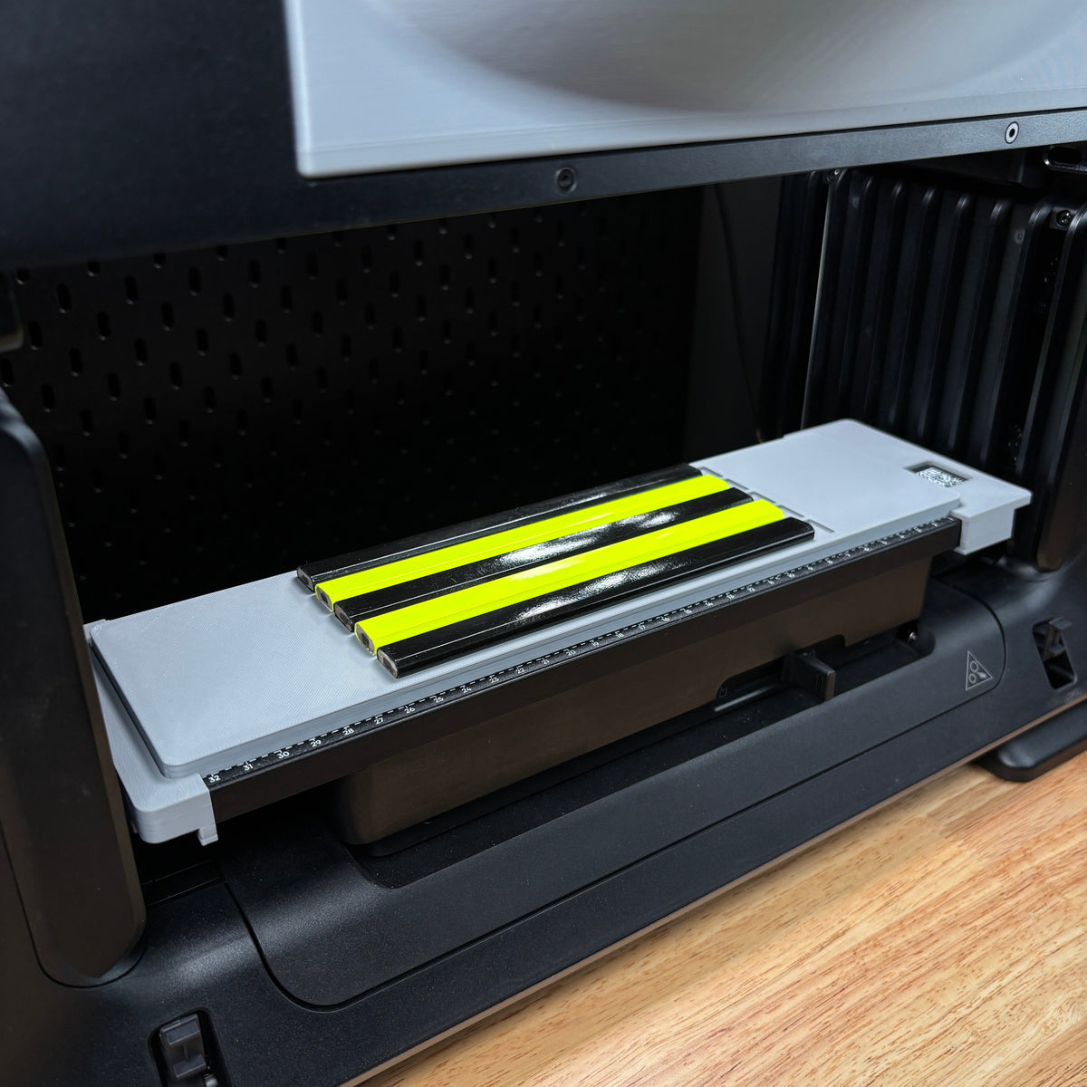 Samcraft carpenter pencil jig on the eufyMake E1 print bed, holding neon yellow carpenter pencils in long channels.