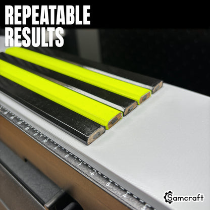Close-up of black and neon yellow carpenter pencils seated in the Samcraft jig, demonstrating repeatable results and the built-in measurement ruler on the eufyMake E1.