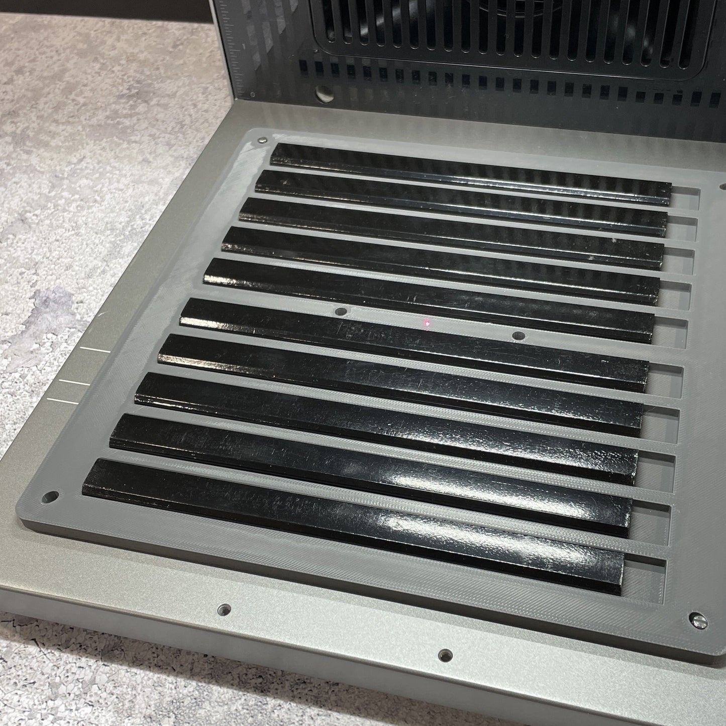 Samcraft carpenter pencil jig on the xTool F2 Ultra bed, holding a full row of flat black carpenter pencils.