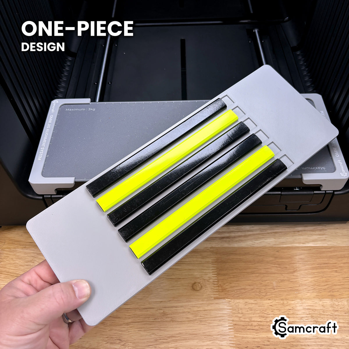 Hand holding the one-piece Samcraft carpenter pencil jig for the xTool Omni, a single molded gray tray loaded with six carpenter pencils.