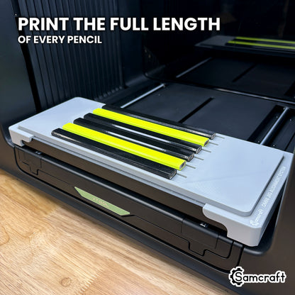 Angled view of six carpenter pencils lying full length in the Samcraft xTool Omni jig, with the wide face of each pencil turned up toward the print head.