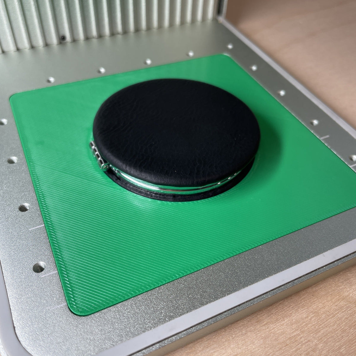 Samcraft compact mirror jig in an xTool F1 laser bed, holding a round black compact mirror.
