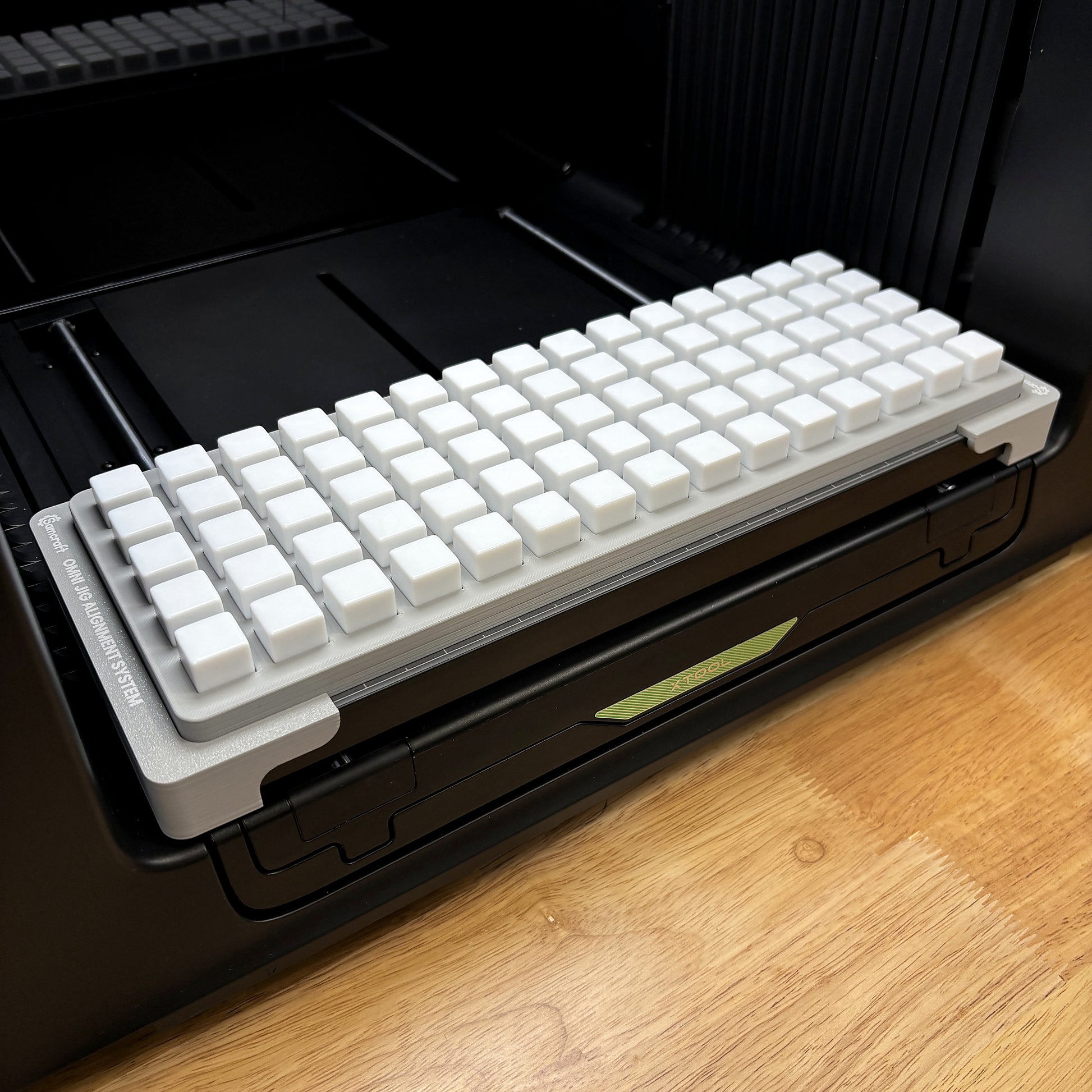 Samcraft 16mm dice jig on the bed of an xTool Omni UV printer, holding a full grid of 75 white blank D6 dice.