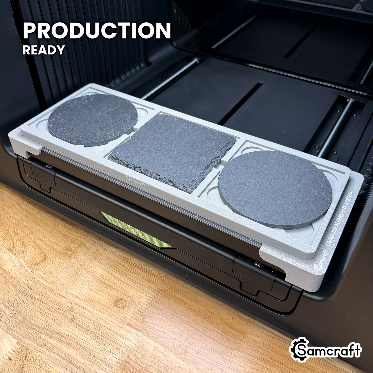 Samcraft 4 inch coaster jig loaded with three slate coasters on the xTool Omni UV printer bed, set up for production runs.