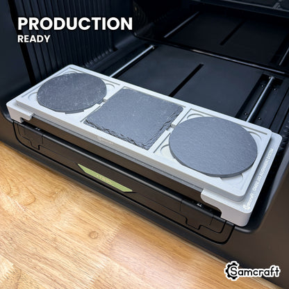 Samcraft 4 inch coaster jig loaded with three slate coasters on the xTool Omni UV printer bed, set up for production runs.