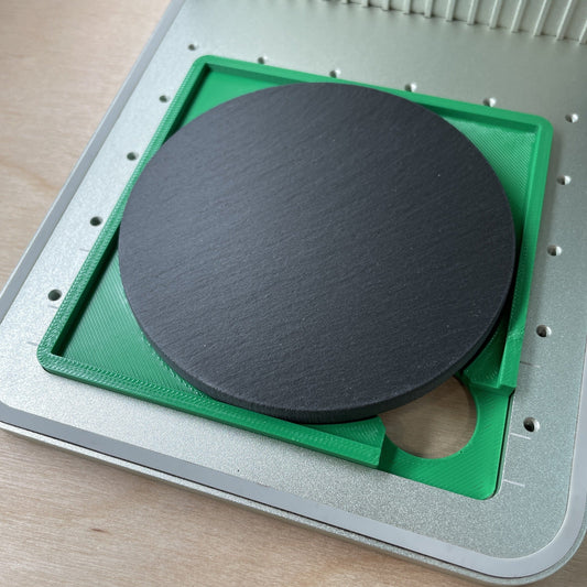 Samcraft 4 inch drink coaster jig in an xTool F1 laser bed, holding a round slate coaster.