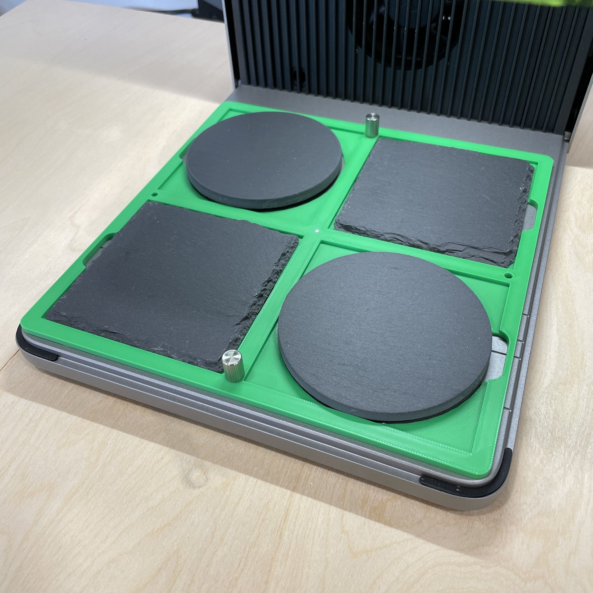 Samcraft green 4 inch drink coaster jig in an xTool F1 Ultra laser bed, holding round and square dark slate coasters.