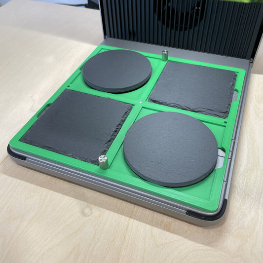 Samcraft green 4 inch drink coaster jig in an xTool F1 Ultra laser bed, holding round and square dark slate coasters.