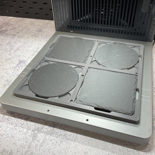 Samcraft 4 inch drink coaster jig on the xTool F2 Ultra bed, holding round and square slate coasters.