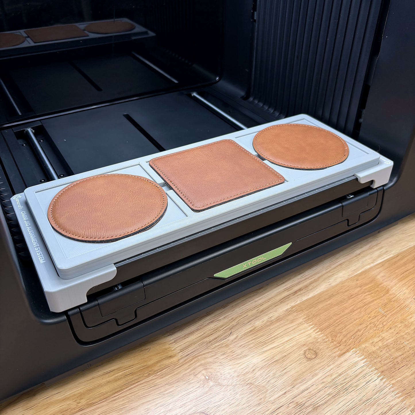 Samcraft 99mm drink coaster jig on the bed of an xTool Omni UV printer, loaded with leatherette coasters.
