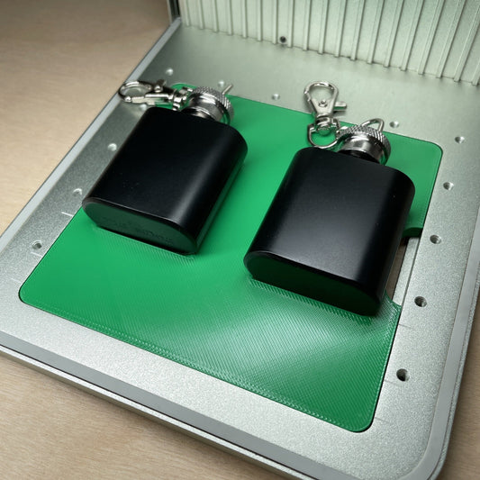 Samcraft flask keychain jig in an xTool F1 laser bed, holding two black keychain flasks side by side.