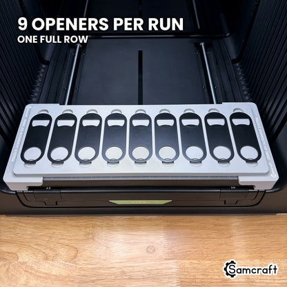 Samcraft jig for the xTool Omni loaded with nine flat metal oval keychain bottle openers, a full row in one pass.