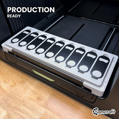 Samcraft opener jig loaded with nine bottle openers on the xTool Omni UV printer bed, set up for production runs.