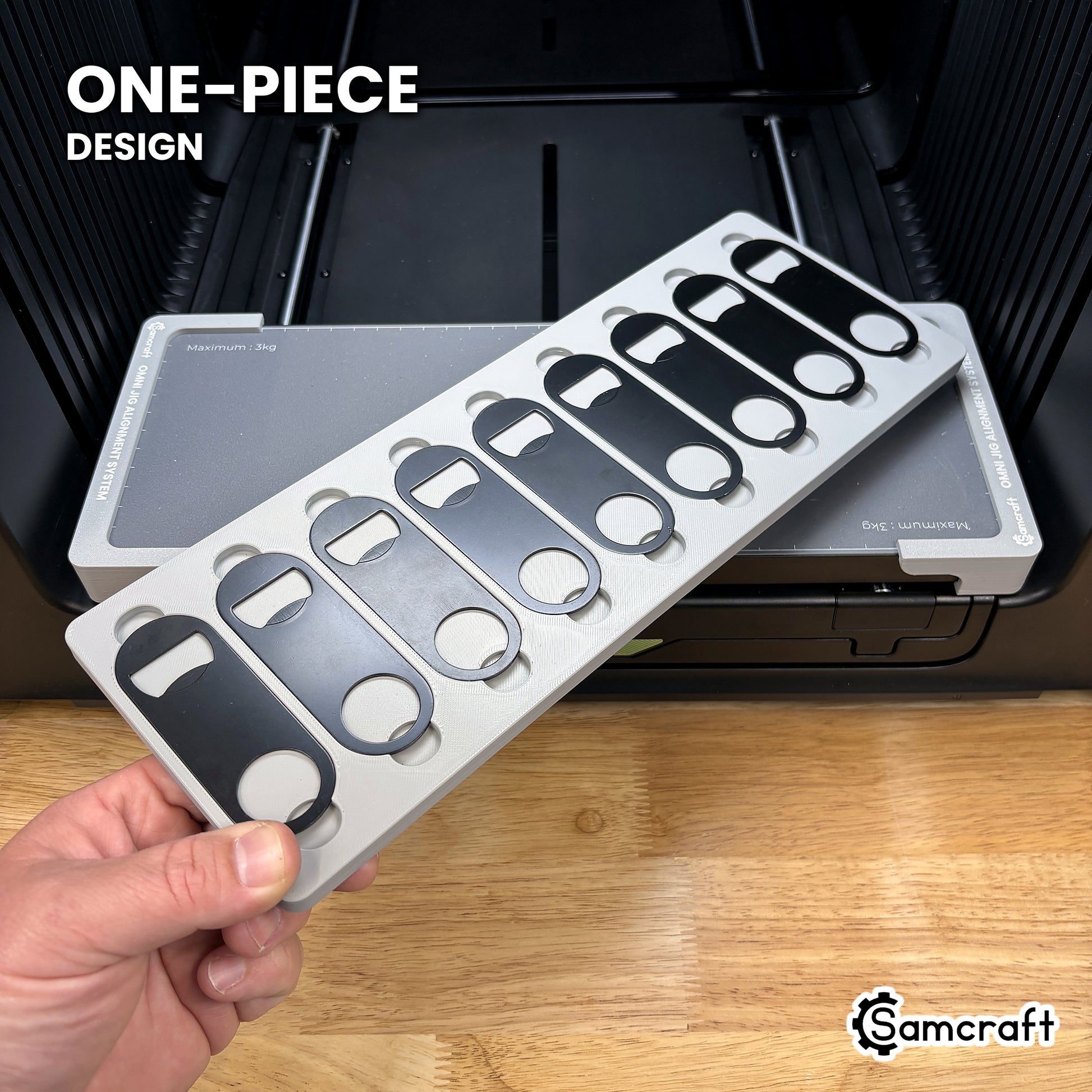 Hand holding the one-piece Samcraft flat metal bottle opener jig for the xTool Omni, nine openers seated in a single molded tray.