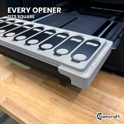 Every flat metal opener seated square in its own pocket across the Samcraft xTool Omni jig, for consistent print placement.