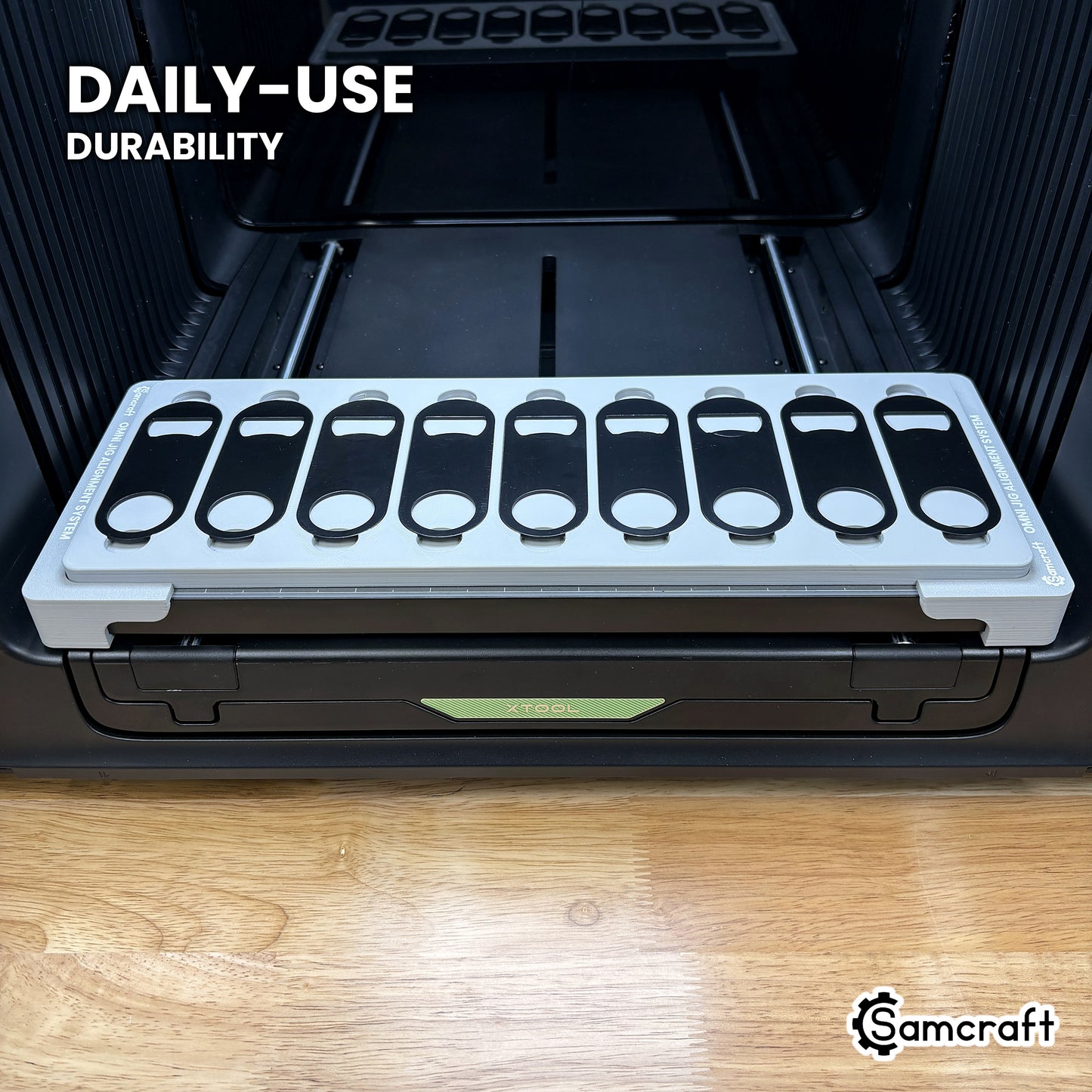 Samcraft opener jig in high-temperature rated plastic holding nine bottle openers on the xTool Omni bed, built for daily-use durability.