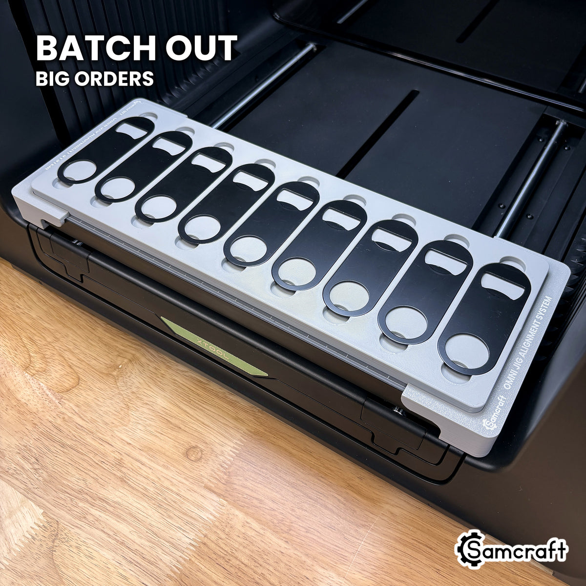 Samcraft xTool Omni opener jig filled with nine flat metal keychain bottle openers, ready for batch and bulk orders.