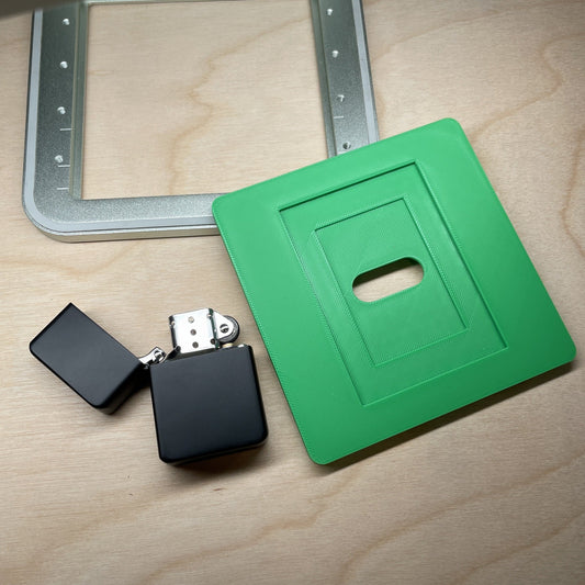 Samcraft flip top lighter jig on a wooden desk with an open black flip top lighter beside it.