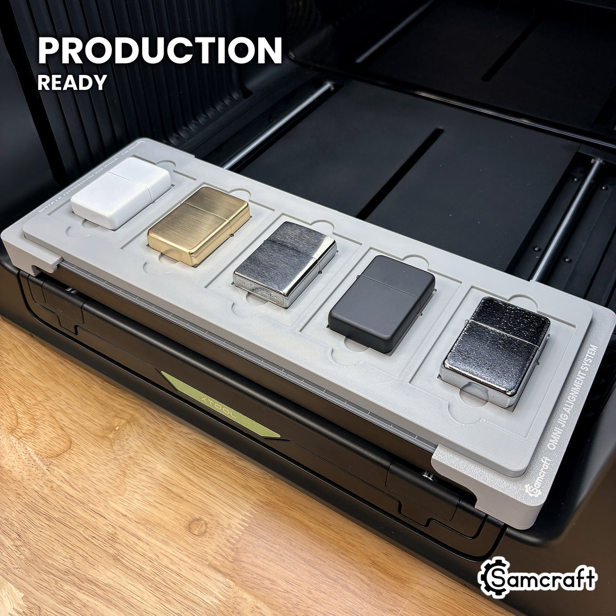 Samcraft lighter jig loaded with five flip top lighters on the xTool Omni UV printer bed, set up for production runs.