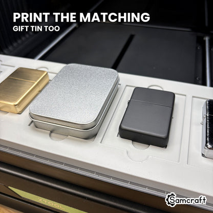 A gift tin case seated beside flip top lighters in the Samcraft xTool Omni jig, so a lighter and its tin can be printed as a matching set.