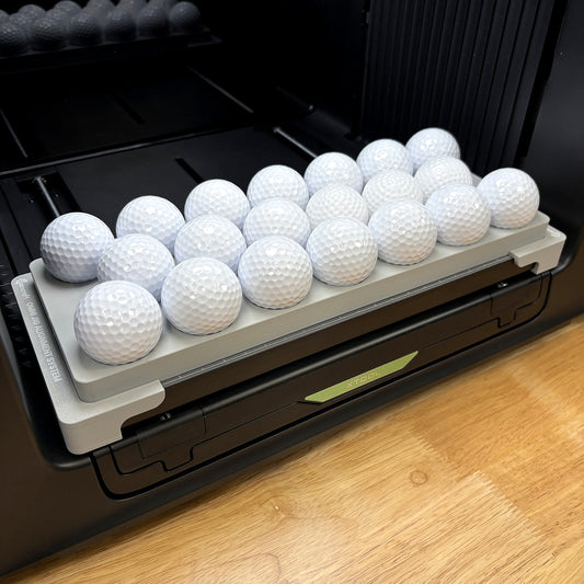 Samcraft golf ball jig on the bed of an xTool Omni UV printer, holding twenty white golf balls in stepped ring pockets.
