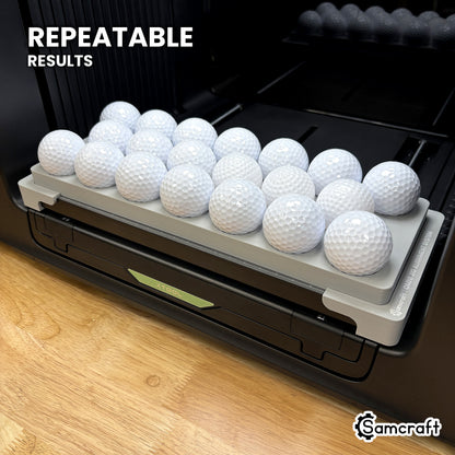 Angled view of the Samcraft golf ball jig on the xTool Omni printer bed with its built-in alignment ruler, for repeatable results.
