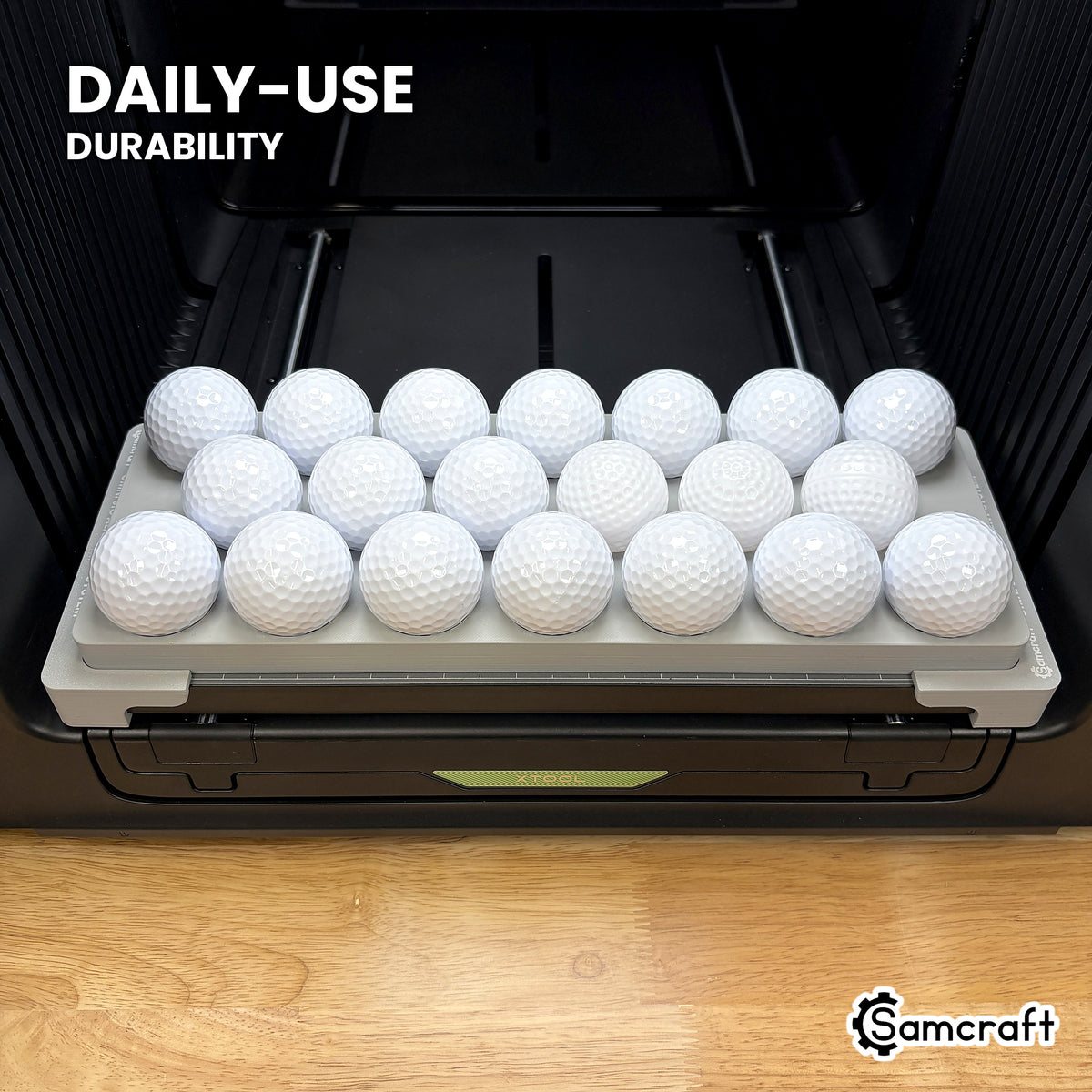 Samcraft golf ball jig in high-temperature rated plastic holding twenty golf balls on the xTool Omni bed, built for daily-use durability.