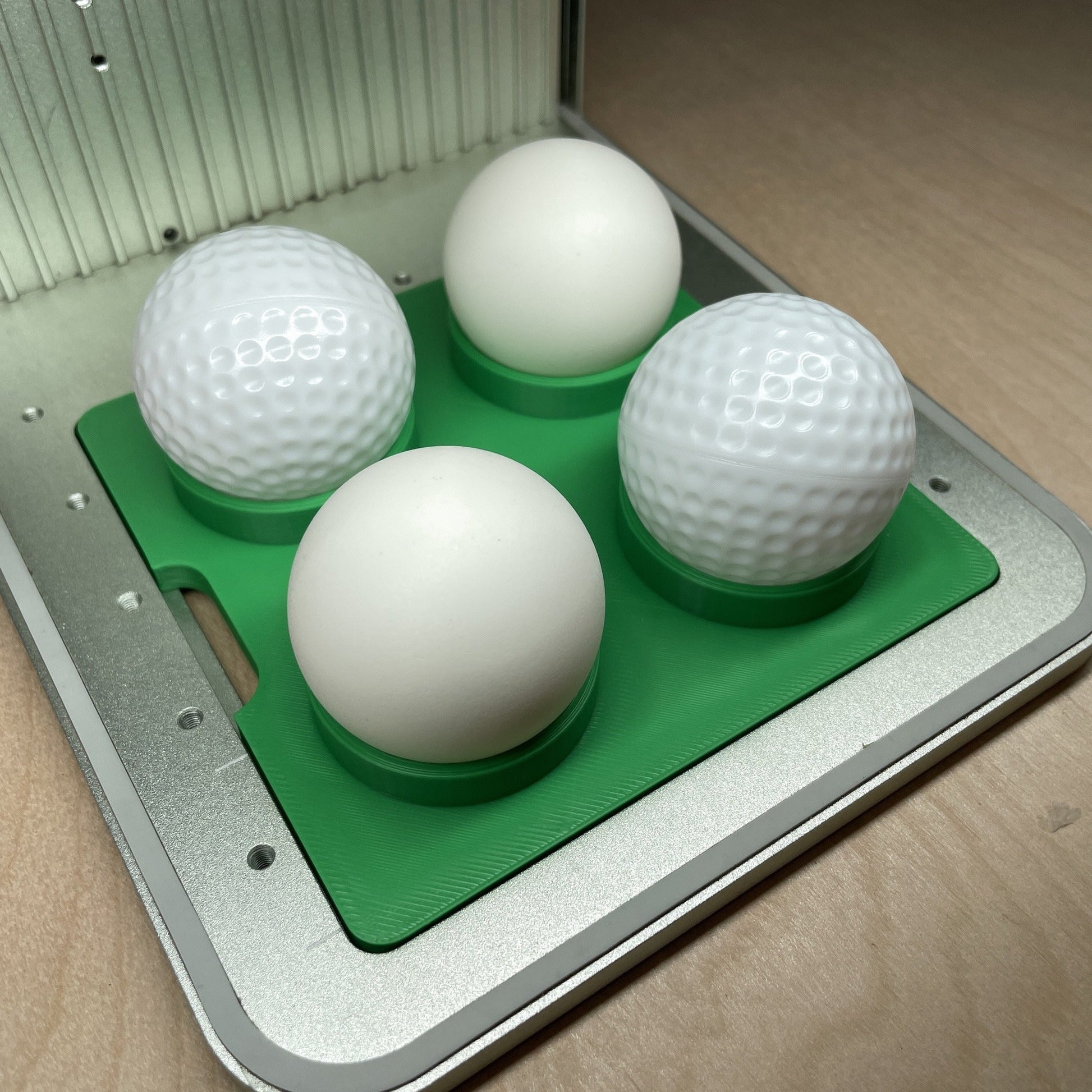 Samcraft golf ball and table tennis ball jig in an xTool F1 laser bed, cradling four white balls.