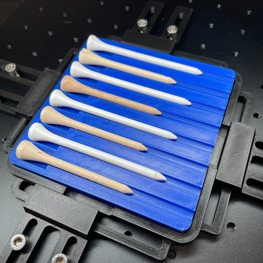 Samcraft blue golf tee jig on a ComMarker laser bed, holding a row of white and natural wood golf tees.