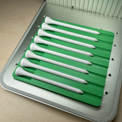 Samcraft golf tee jig in an xTool F1 laser bed, holding eight white golf tees angled across the jig.