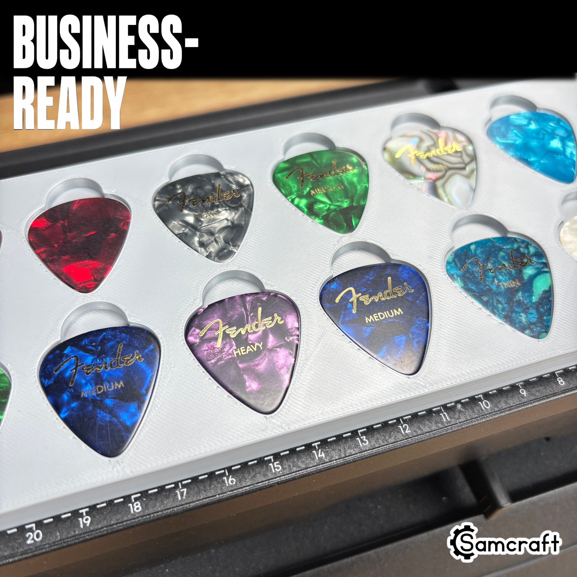 Guitar Pick Jig for the eufyMake E1 — close-up of colorful Fender celluloid guitar picks in red, blue, purple, green, and abalone pearl finishes held in the gray 3D-printed tray with built-in alignment ruler, ready for business-scale personalization.