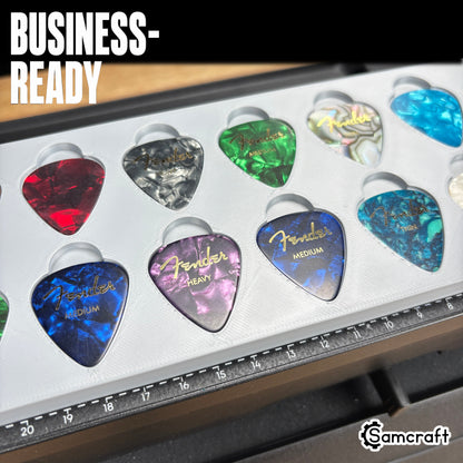 Guitar Pick Jig for the eufyMake E1 — close-up of colorful Fender celluloid guitar picks in red, blue, purple, green, and abalone pearl finishes held in the gray 3D-printed tray with built-in alignment ruler, ready for business-scale personalization.